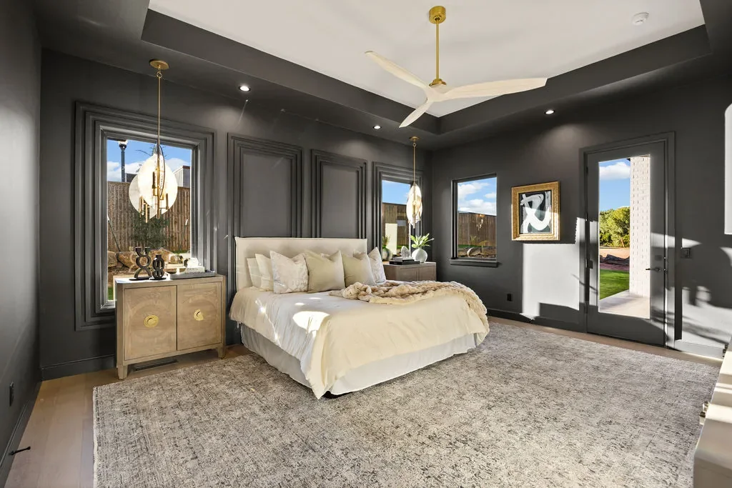 Black-paneled primary bedroom with garden doors and brass accents