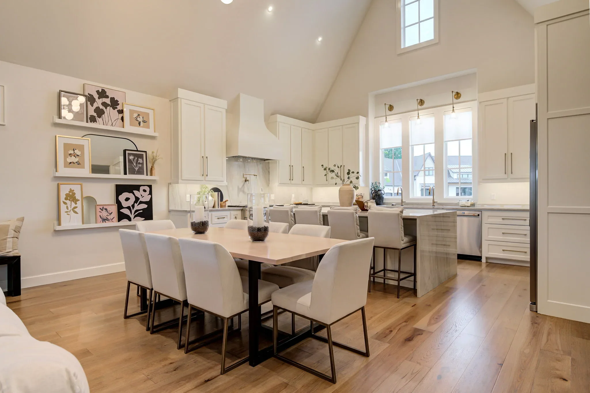 Dining table beside the white chef's kitchen and marble island